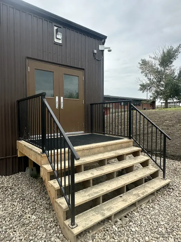 Exterior security camera installed above the entrance stairs of a metal-clad commercial building