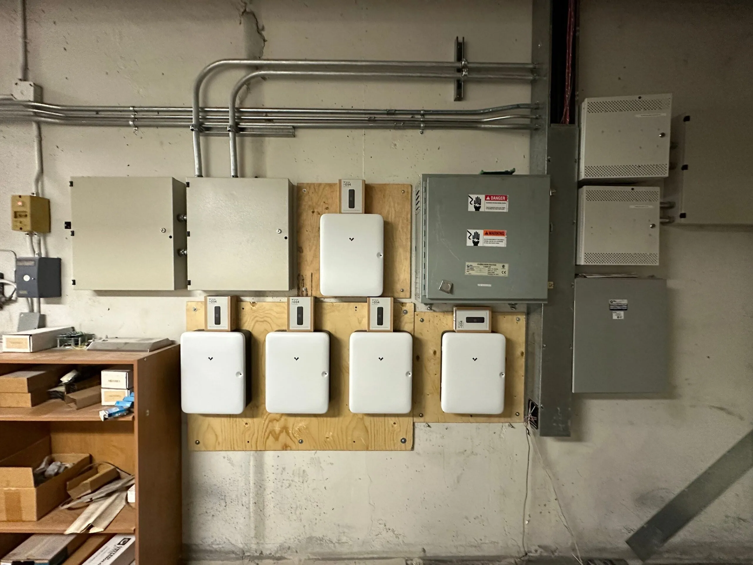 Multiple access control and power distribution panels mounted on a concrete wall in a building utility room