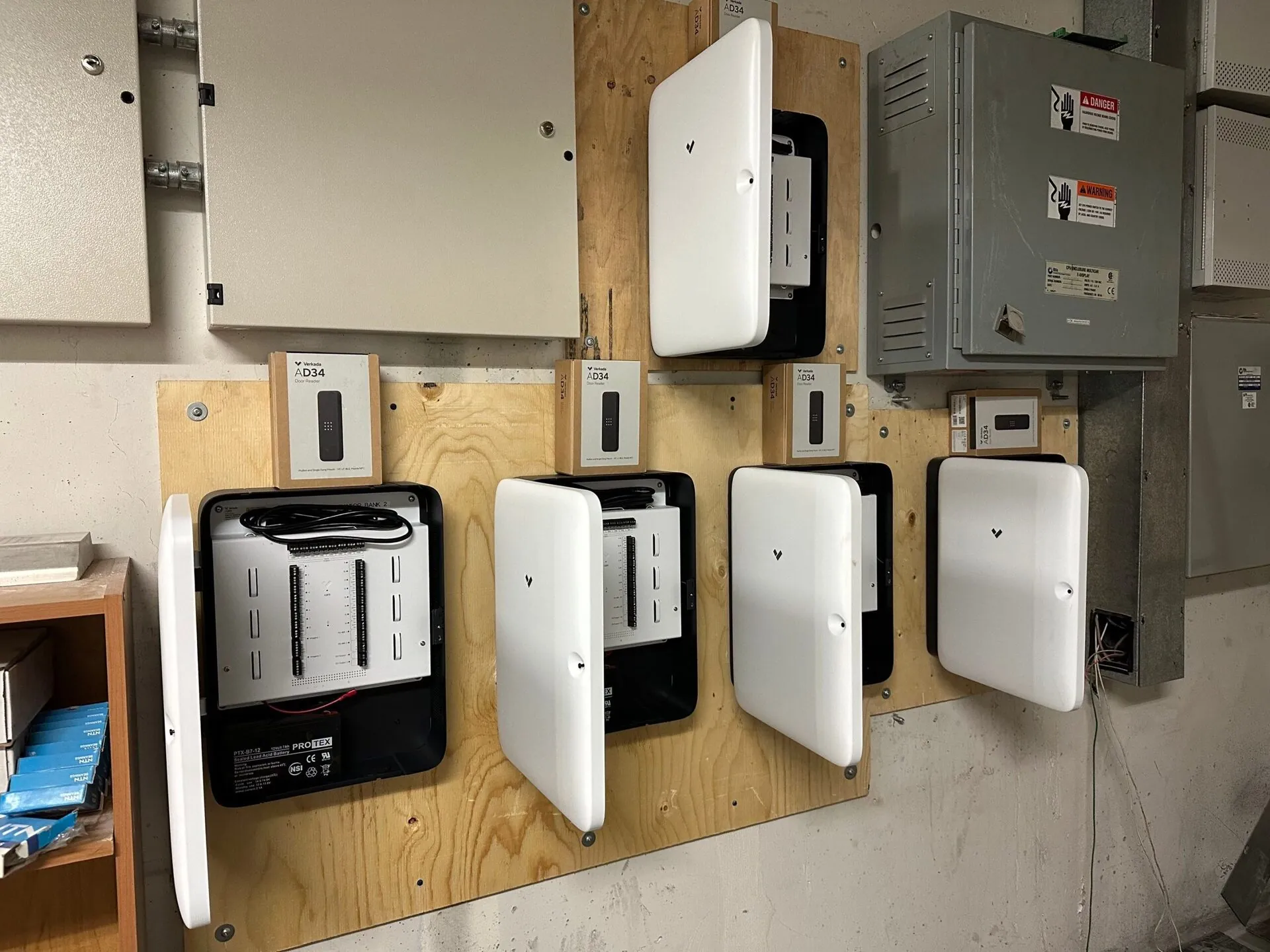 Close-up of access control panels and door controller boards mounted on plywood backing in an equipment room