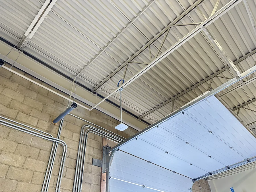 Wireless access point installed near a loading dock overhead door inside an industrial warehouse