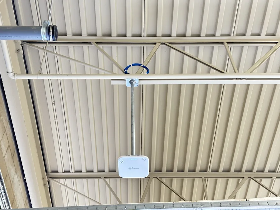 Wireless access point mounted on warehouse ceiling rafters for facility-wide Wi-Fi coverage