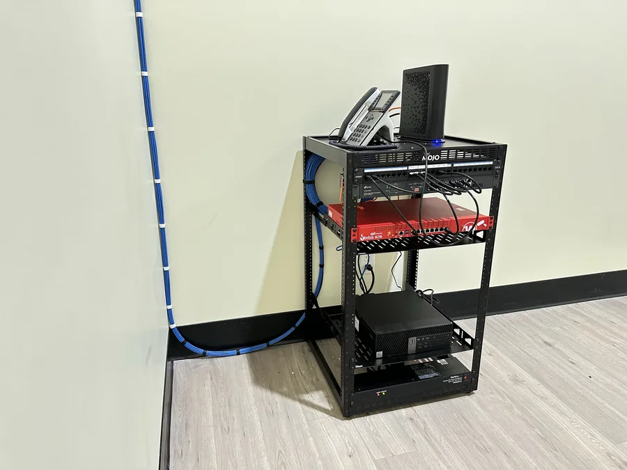 Networking equipment rack with VoIP phone, switch, and firewall connected via structured cabling
