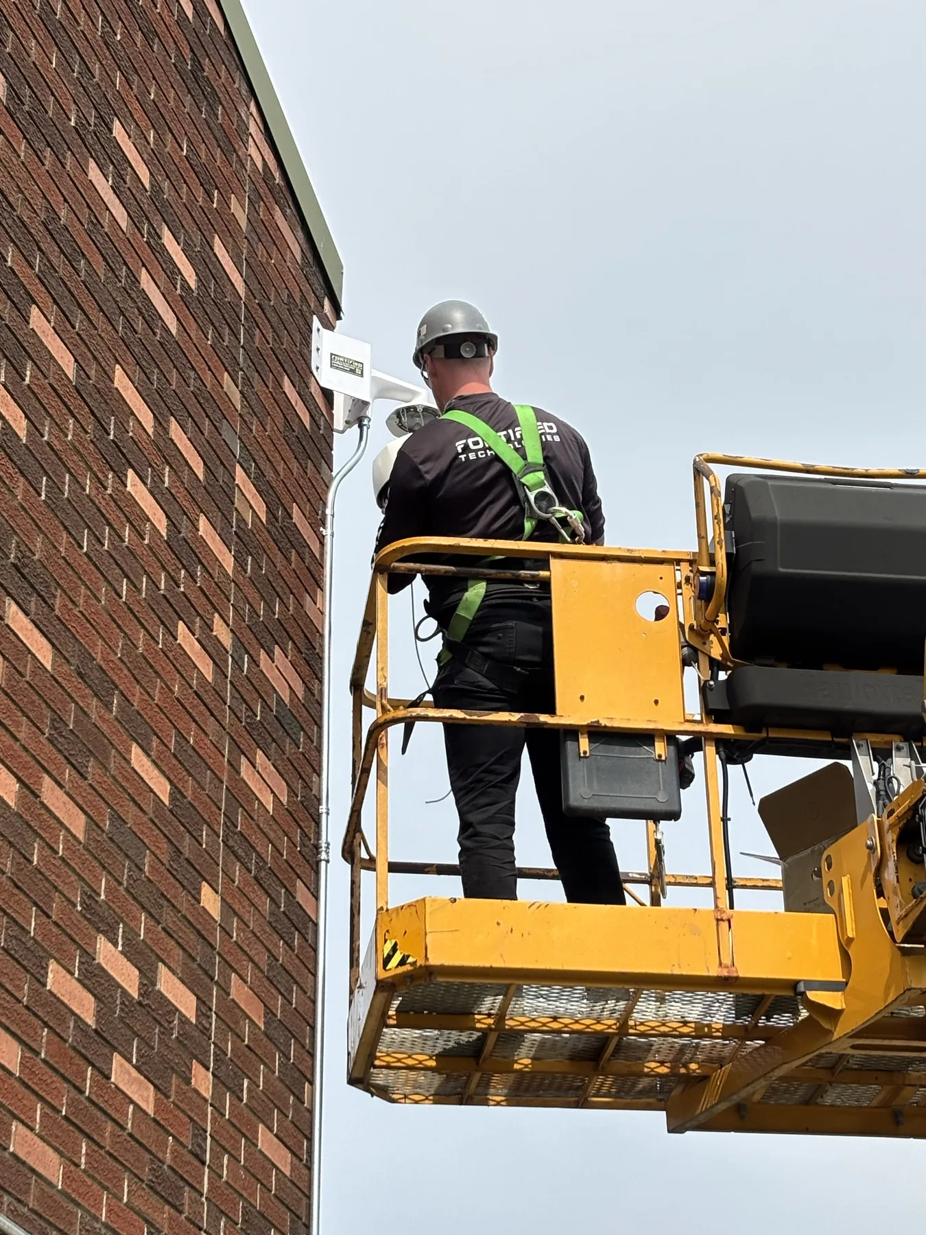 Technician installing an exterior security camera from an elevated work platform