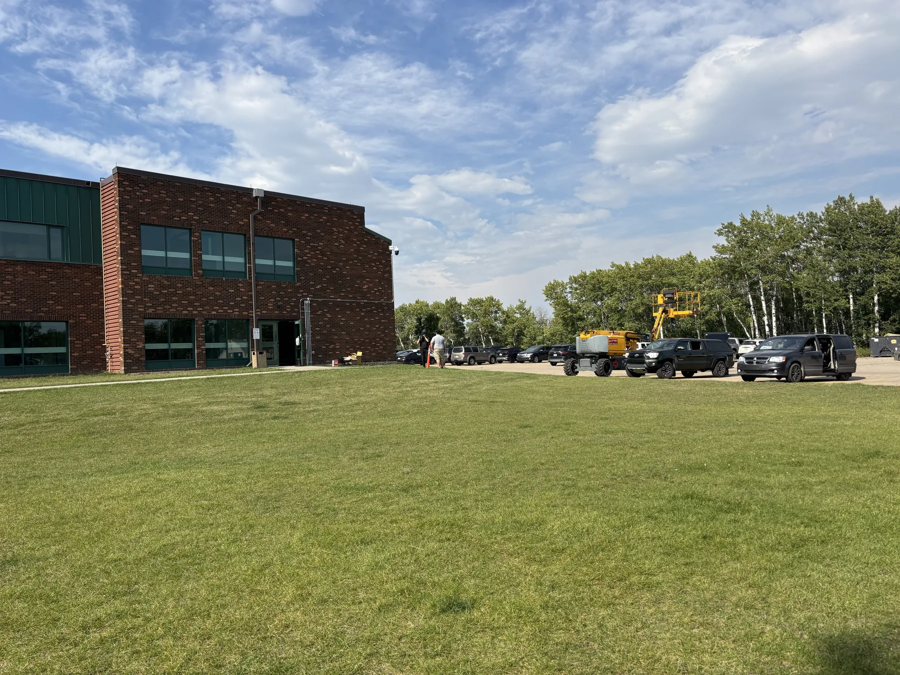 Technician installing security equipment from an elevated work platform beside a brick commercial building
