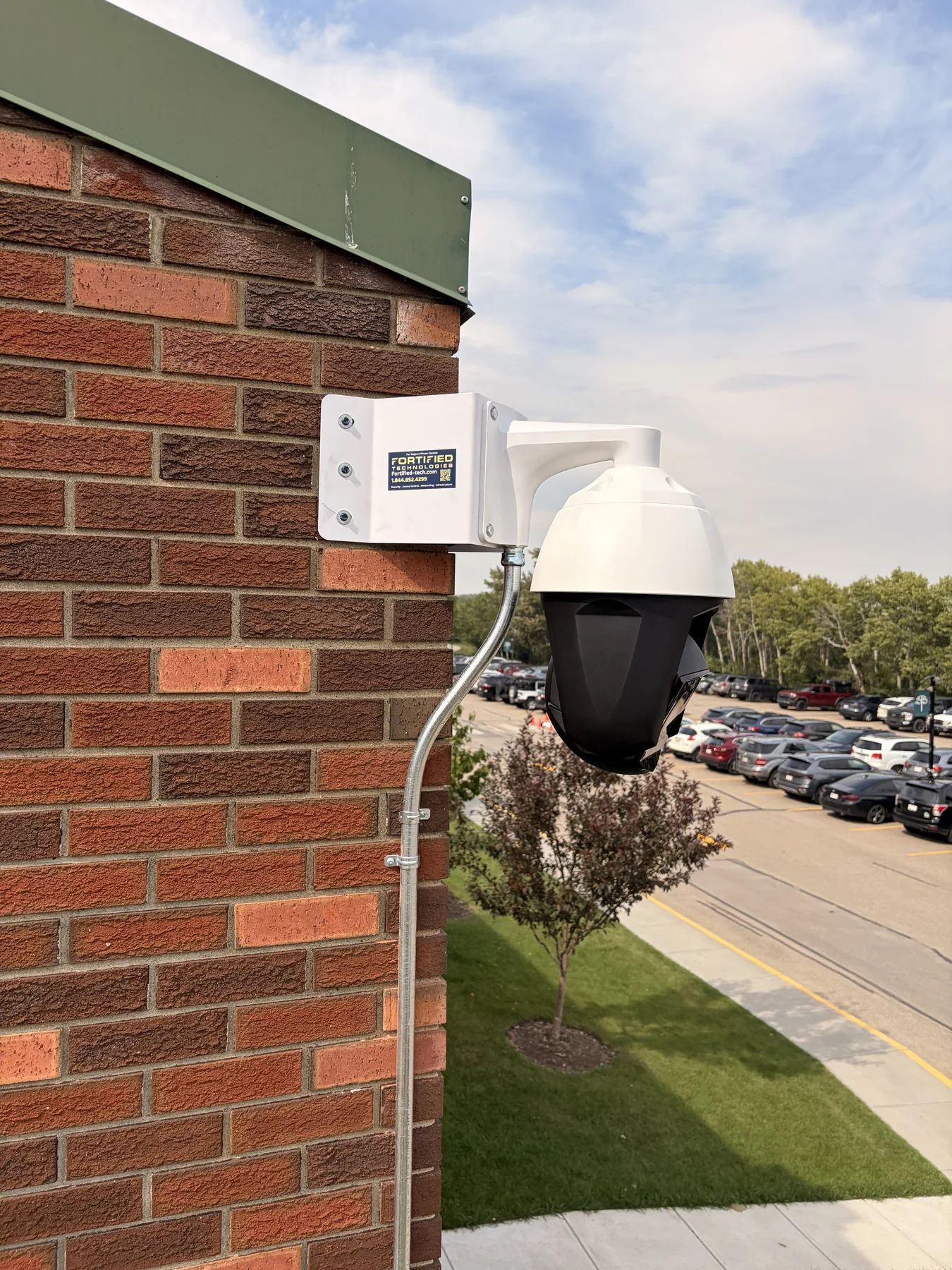 Close-up of an exterior security camera mounted on a brick commercial building wall