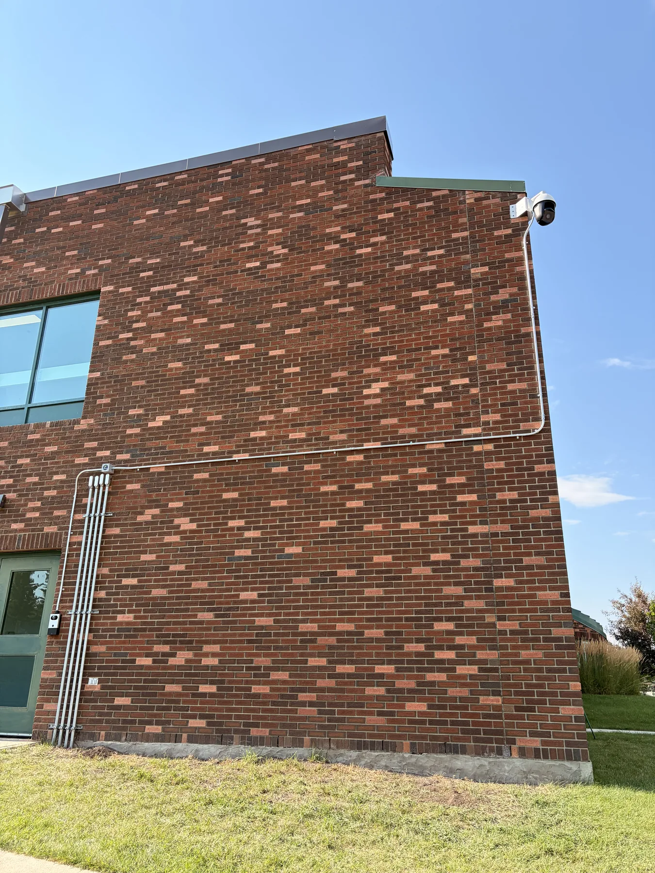 Security camera and conduit run installed along the exterior of a brick commercial building