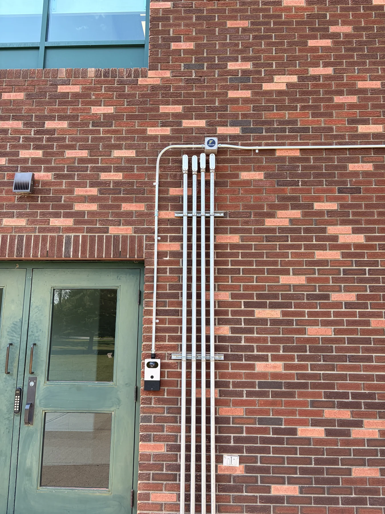 Security camera and conduit installed beside an exterior commercial entry door