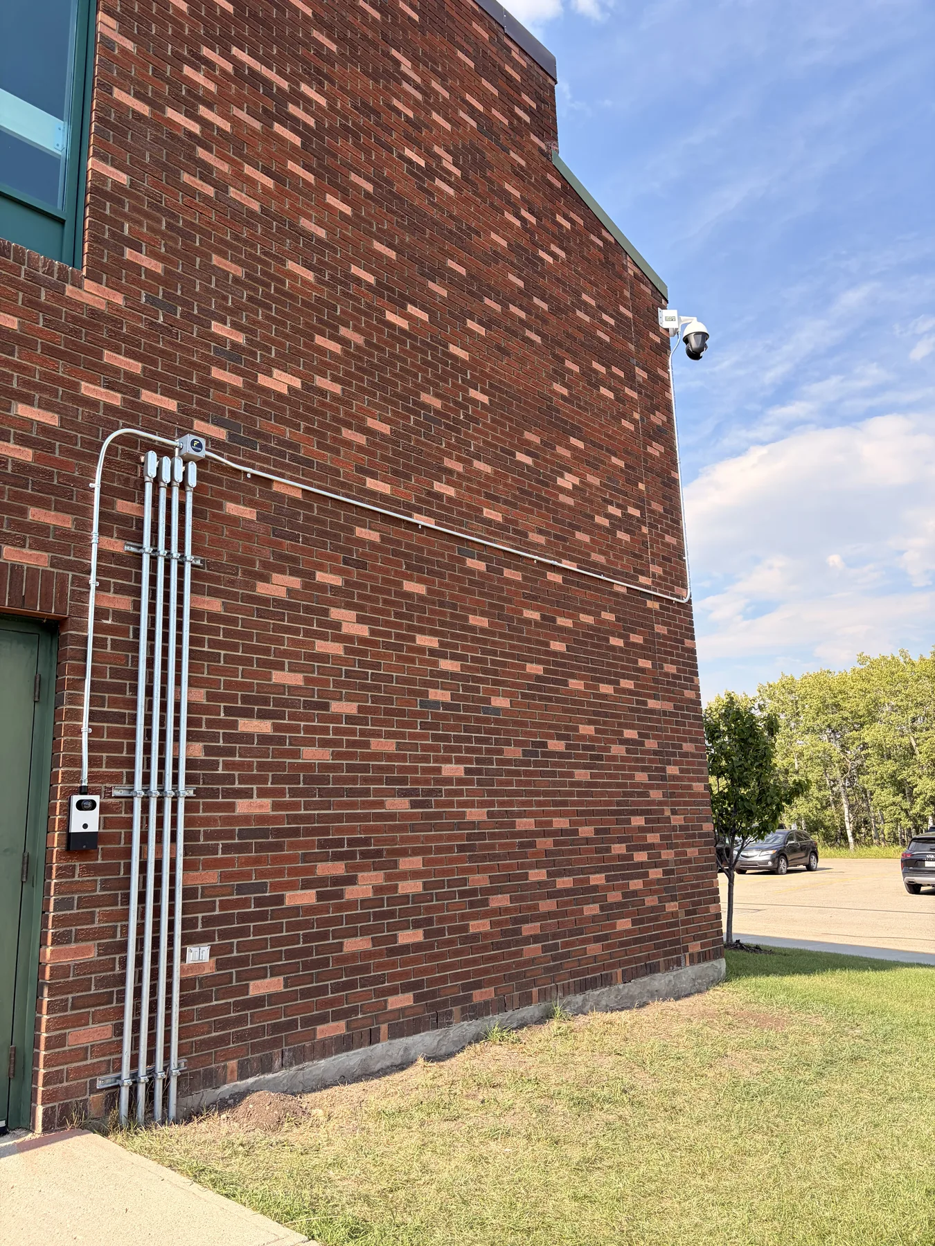 Exterior security camera and conduit installed on a brick commercial building wall